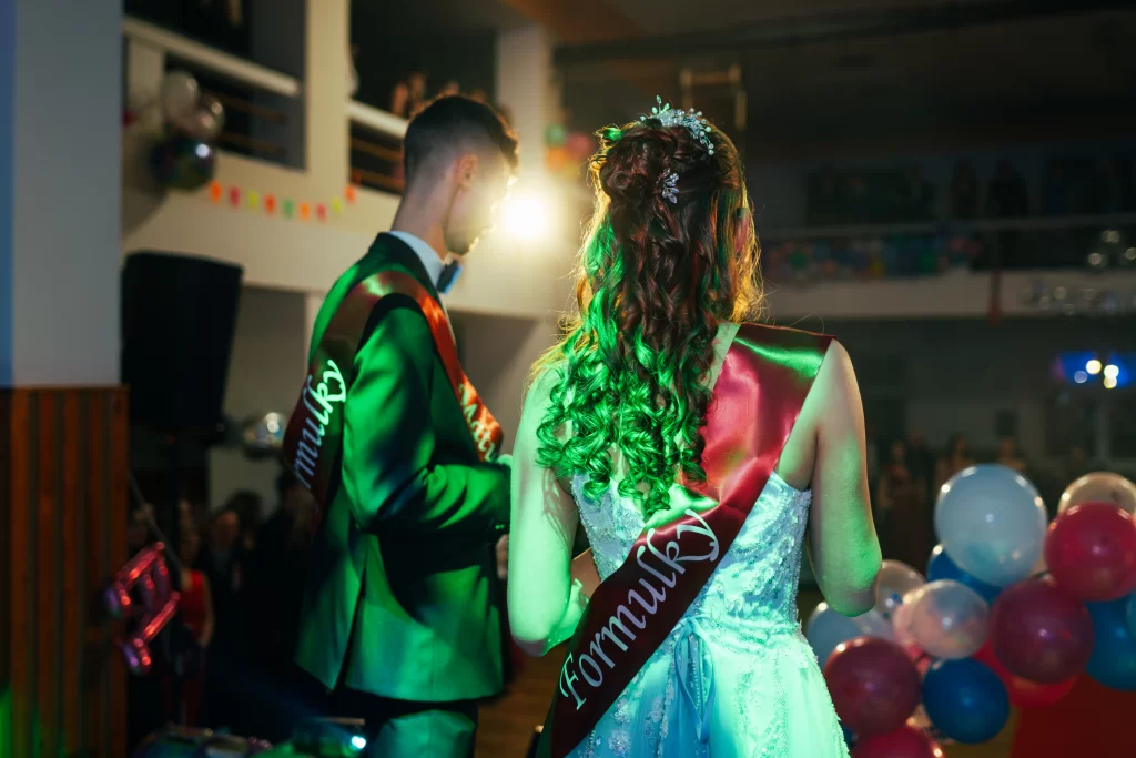 Maturant a maturantka se šerpami v zeleném světle, pohled zezadu.