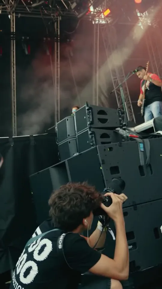Kameraman natáčí vystoupení z boku festivalového pódia.